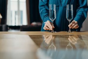 What is the correct way to hold a wine glass according to formal dining etiquette?